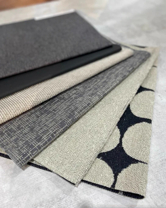 A group of dark neutral fabric swatches in shades of gray and black in varying patterns.