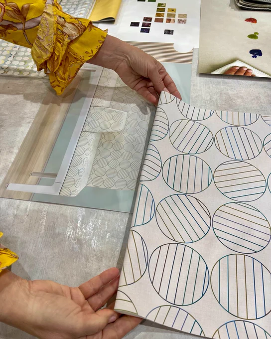 A Designtex fabric swatch is held up that has blue lined circles on a white background.