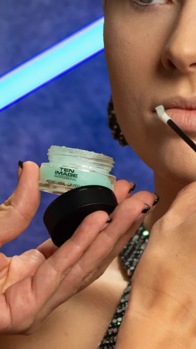 A model applies Sugar Frost Lip Scrub by Ten Image Professional to her lips.