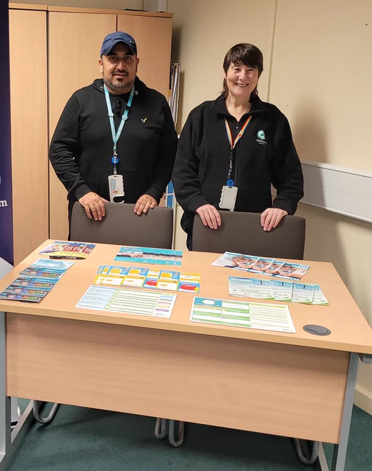 Image of Oldham Council staff smiling behind a desk