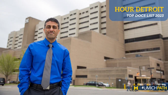 Dr. Rohit Mehra stands in front of University of Michigan Hospital. 