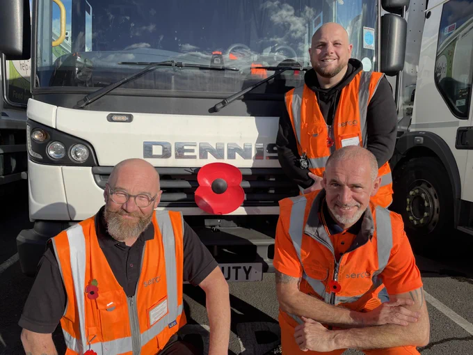 Image of a bin lorry with a large plastic poppy on the front and three men in orange high visibility jackets