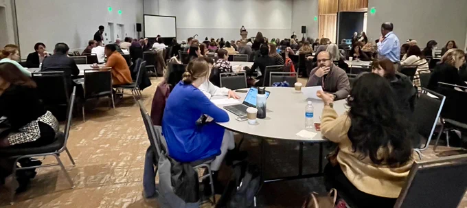 Room full of people at round tables talking