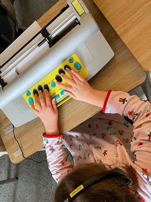 A girl typing on a Mountbatten Brailler.