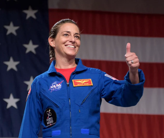 Nicole Mann poses giving a thumbs up in front of the American flag. Credit: NASA/Bill Ingalls 