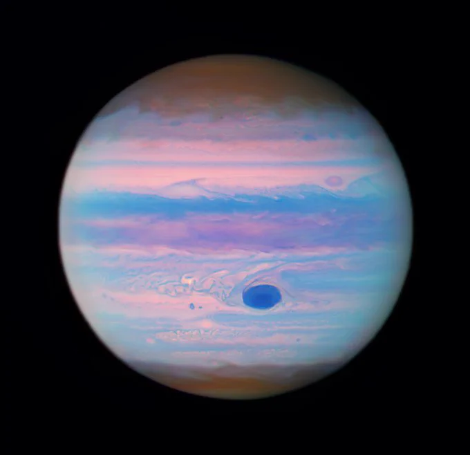La Grande Macchia Rossa del pianeta, che l'occhio umano vede rossa, appare più scura in questa immagine agli UV poiché a queste lunghezze d'onda le particelle di foschia ad alta quota assorbono la luce. Immagine composita a colori dal telescopio spaziale Hubble di NASA/ESA.