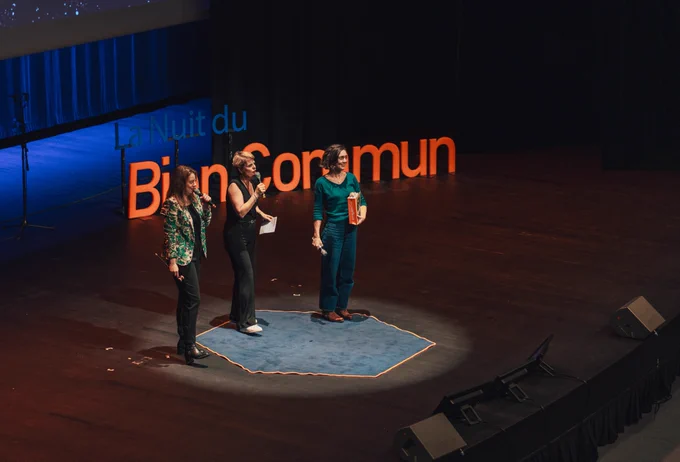Sophie Blain, directrice de l'association avec un livre tactile dans les mains sur la scène du palais des congrès de Dijon aux cotés des deux animatrices de la soirée