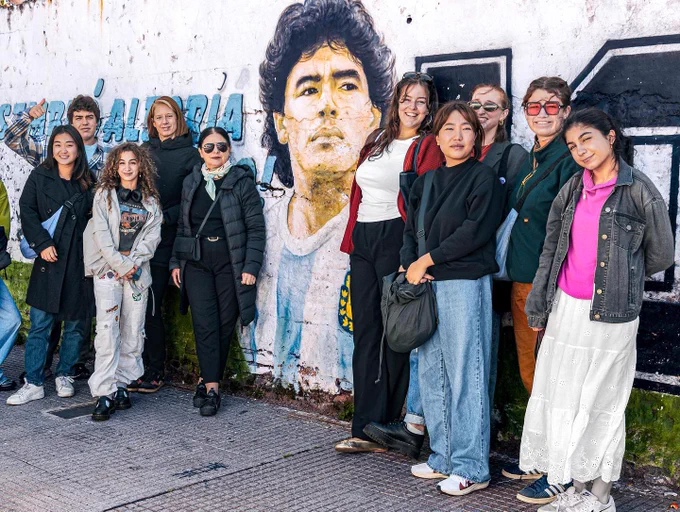 students posing in front of a mural of a soccer player