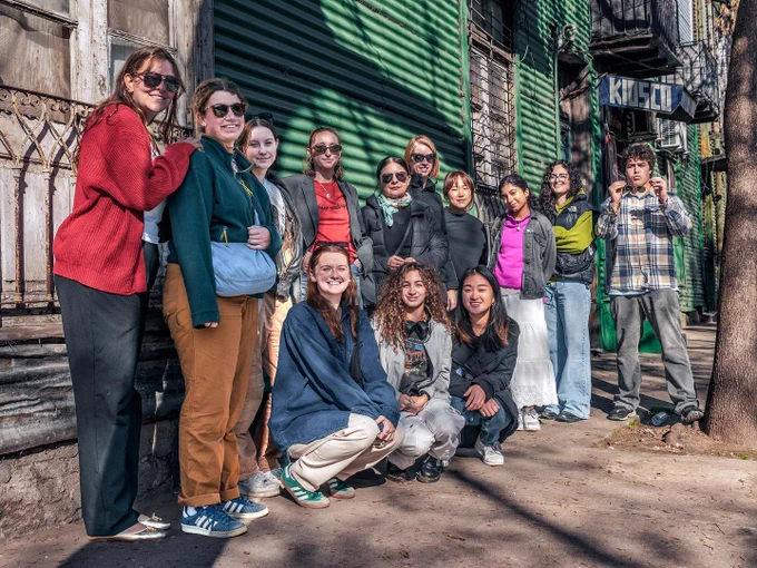 Students posing in front of a green shuttered storefront in the LA Boca neighborhood