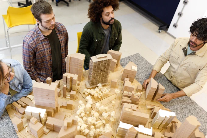 Un professeur enseigne l'urbanisme à des étudiants à l'aide d'une maquette de ville.