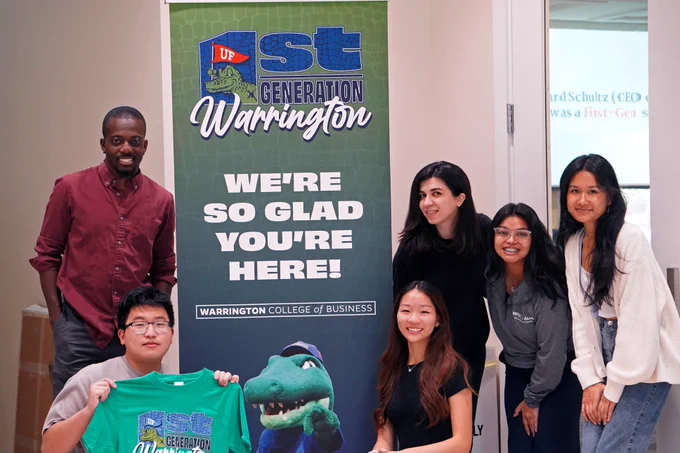 A group of first generation students pose for a photo with a staff member and some Warrington swag. 