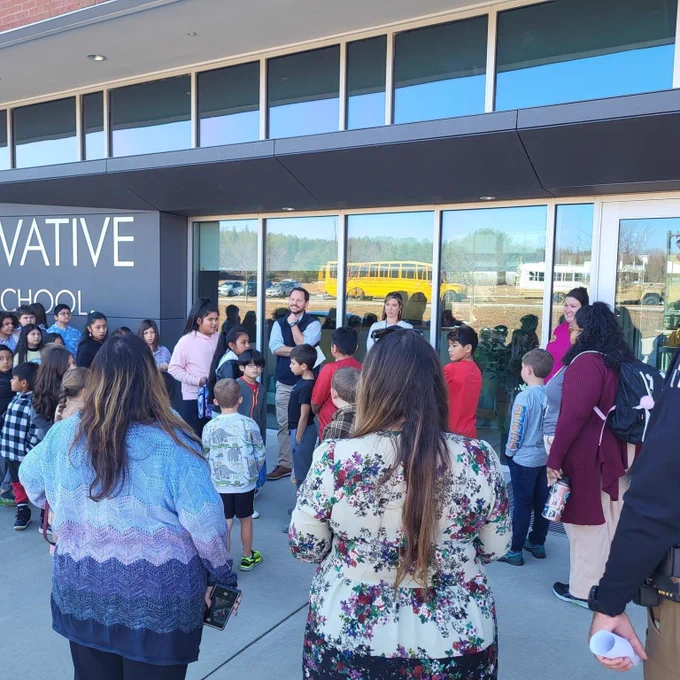 Dana students and Innovative High School staff standing outside the school talking after getting off the bus.