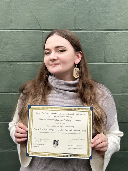 Olivia Anderson holds her Native American/Indigenous Student Research Abstract Award, received at SACNAS 2023.