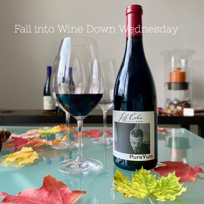 A bottle of Jeff Cohn Cellars Pure Yum on a table with fall Maple leaves with a glass of wine.