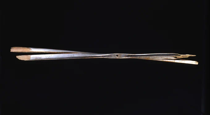 Propeller from original Wright Flyer. The image is of two pieces of wood crossed over each other with a silver coating.