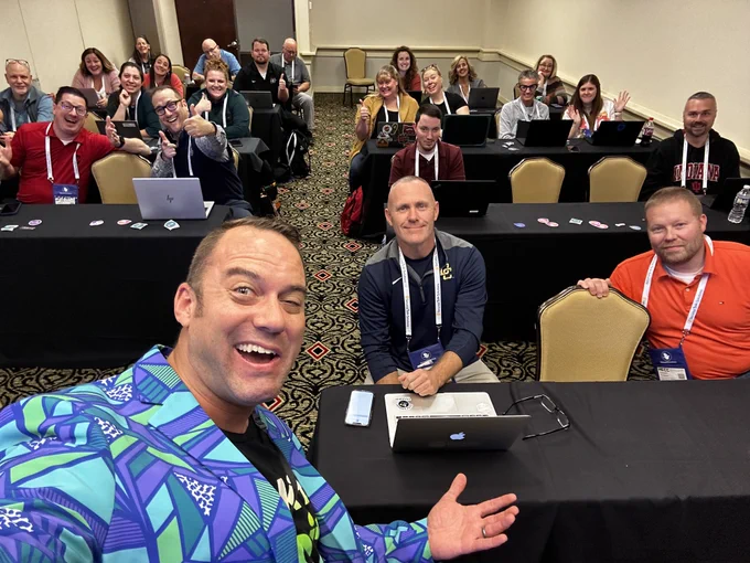 Andy taking a selfie with a room full of educators, administrators, and school technicians in a conference room