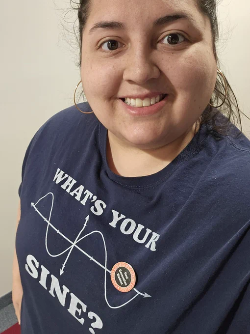 Jenna wearing a tshirt that reads "What's Your Sine?" and a button that reads First Generation Student. 