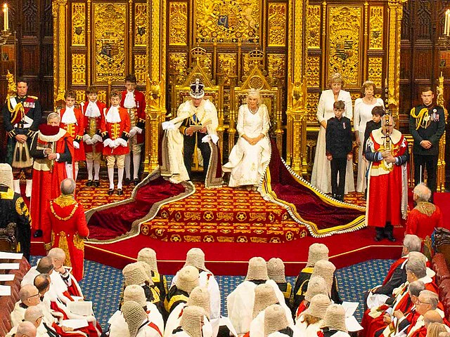 King Charles III and Queen Camilla sit on thrones to formally open the new session of the Houses of Parliament.

Image credit: House of Lords 2023, photography by Roger Harris, Creative Commons Attribution 2.0