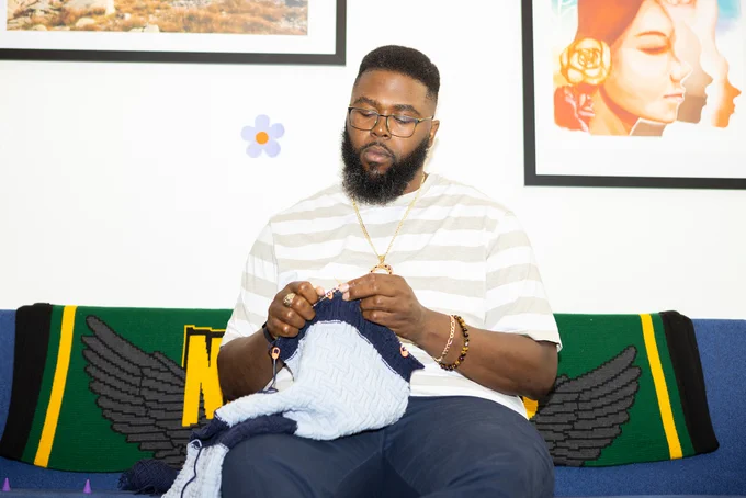 A photo of a Black man knitting.