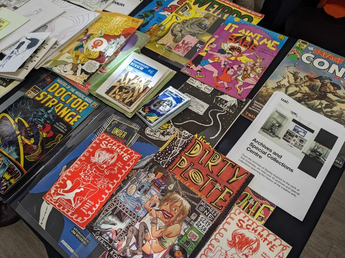 Various colourful comic books and small-press publications laid out on a table.