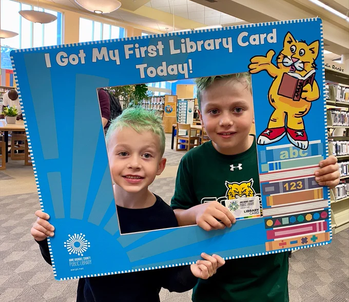 Brothers Connor and Dylan hold up a sign that says "I got my first library card today!"
