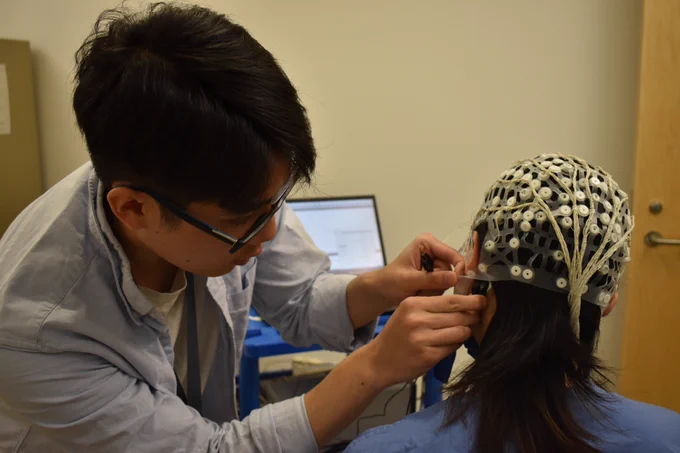 Martin Keung, Clinical Research Assistant in Dr. McKeown’s lab, attaching the stimulator's lead to an electrode positioned over the research participant's vestibular system.