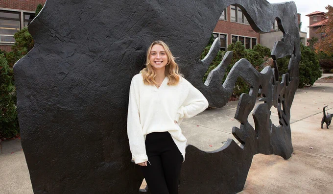 Madeline Brod posing in front of the Continuum Sculpture outside of the Purdue University College of Veterinary Medicine.