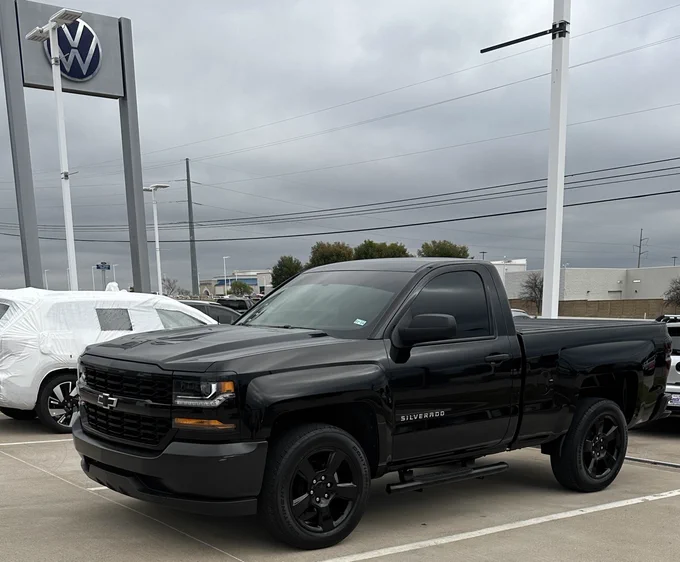 a black 2018 chevy silverado in profile view in the Southwest Volkswagen parking lot on a cloudy day.
