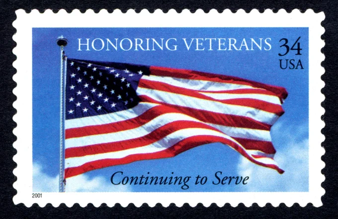 Postage stamp depicting realistic image of American flag on flagpole waving against a blue sky.