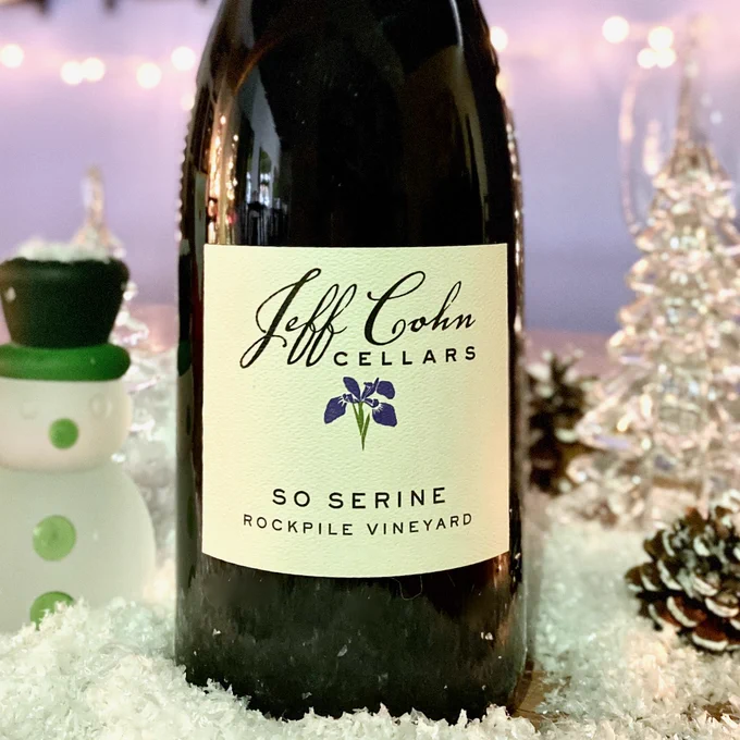 A magnum of So Serine on a snowy table with a glass trees, snowman, flocked pinecones and wine stems.