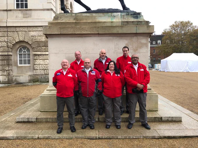 A group of 7 volunteers wearing red and grey red cross uniform, they are standing in front of the Cenotaph in London