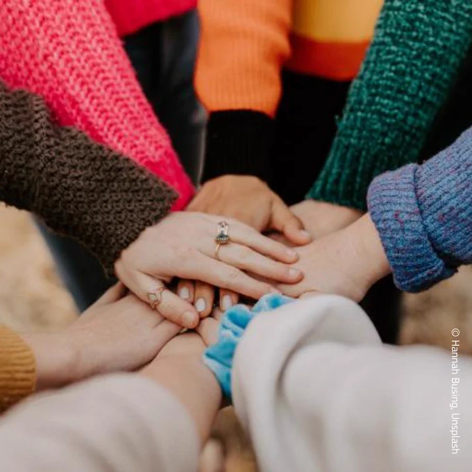 The image shows a group of individuals holding hands together.
