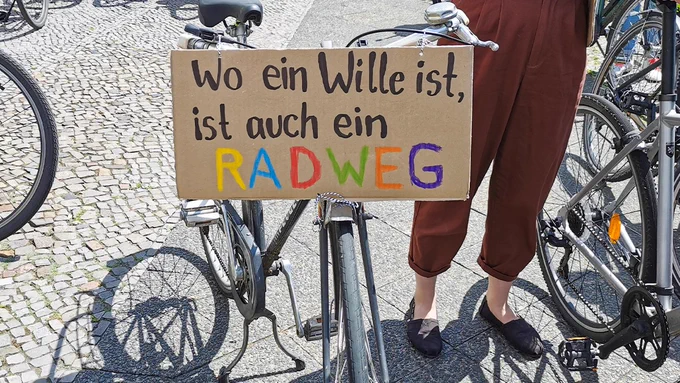 Ein Fahrrad, auf dem ein Demoschild aus Karton angebracht ist. Darauf steht: "Wo ein Wille ist, ist auch ein Radweg."