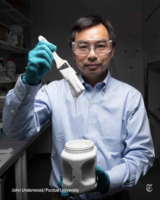 Xiulin Ruan, a professor at Purdue University, wears goggles and holds a paint brush dripping with white paint. His other hand holds a plastic container of the white paint. Photo credit: John Underwood/Purdue University
