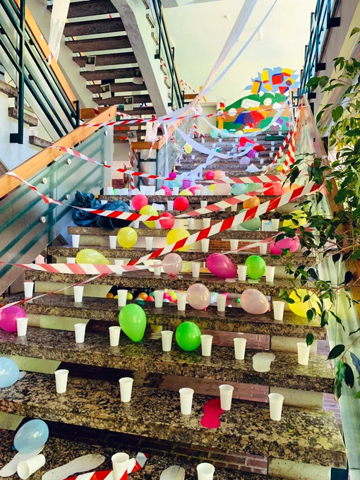 Auf den Treppen der Schule stehen Becher und  Luftballons. Alles ist mit Absperrband verhängt. Abschlussstreich.