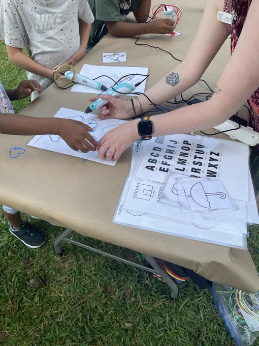Small children use a 3-D pen to draw outlines of various shapes.