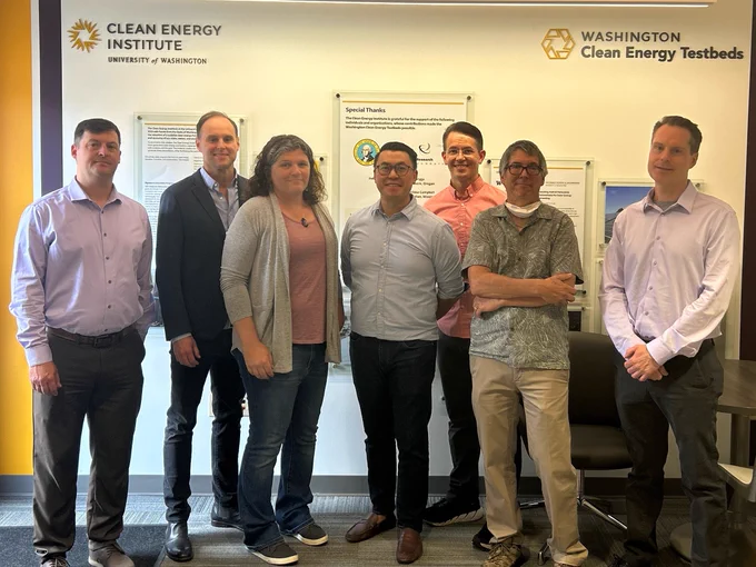 Mike Pomfret, Brian Screnar, Emma Romig, Jared Silvia, Dan Schwartz, and David Ginger pose with WA State Senator Joe Nguyễn in the lobby of the Washington Clean Energy Testbeds facility. 