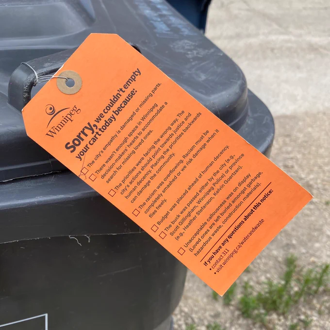 Orange tag affixed to handle of garbage bin. Text reads: Winnipeg
Sorry, we couldn't empty your cart today because:
The city's empathy is damaged or missing parts.
There wasn't enough space in Winnipeg decision-makers' hearts to accommodate a search for missing loved ones.
The priorities were facing the wrong way. The city's actions should point towards justice and human decency. Placing the priorities backwards can damage the community.
The racism was overflowing. Racism must be completely smashed or we risk damage when it flies freely.
Budget was placed ahead of human decency.
The buck was passed either by the city (e.g., Scott Gillingham, Winnipeg Police) or province (e.g., Heather Stefanson, Kelvin Goertzen).
| Unacceptable callousness was on display
(Loved ones are left buried amongst garbage, hazardous waste, construction materials).
If you have any questions about this notice:
• contact 311
• visit winnipeg.ca/waterandwaste