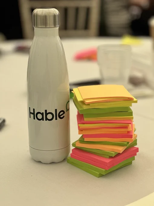 White water bottle next to a stack of post-it notes 