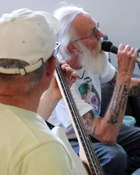 Man singing into a microphone next to a man playing guitar