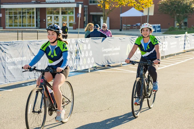 Two cyclists in green BellRinger jerseys cross the finish line