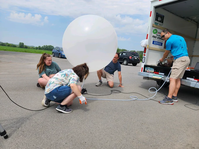 UAlbany students and researchers inflating a large white weather balloon.