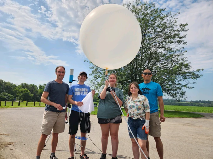 UAlbany students and researchers smiling for a picture while one student holds an inflated weather balloon.