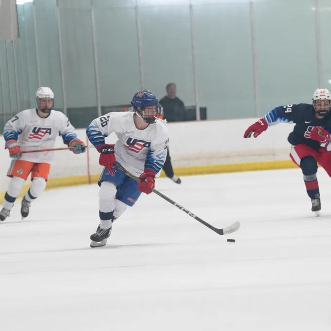 Team White player skates down the ice with the puck 