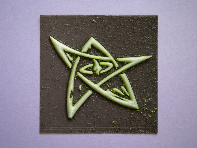 An Elder Sign from the Cthulhu Mythos, 3d printed in 3 colors: a very dark brown or soft black background, vibrant green outline, and soft white inside.