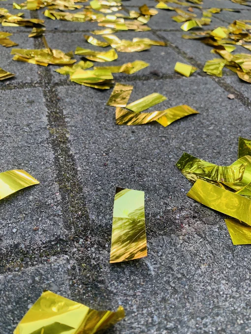Goldenes Konfetti liegt auf grauen Pflastersteinen.