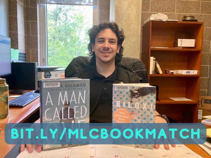 Zach, a smiling white man with curly black hair and a black polo, sits behind two books: 'A Man Called Ove' by Frederick Backman and 'Biloxi' by Mary Miller.