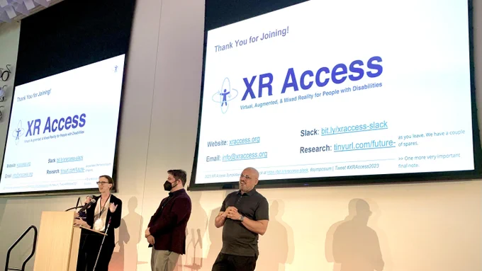 Picture of Shiri Azenkot and Dylan Fox on stage at the end of the XR Access Symposium with a slide thanking people and giving links to more info