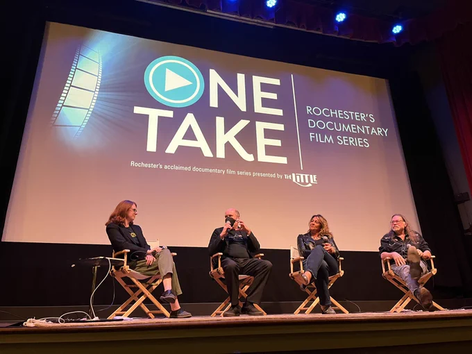 Four people on a movie theater stage.