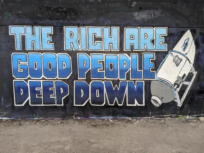 Mural on a black wall featuring the titan submersible and the words "The rich are good people deep down" in blue